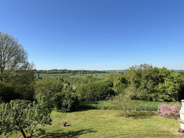 Entourée de prairies, nichée sur un vallon, cette propriété profite d'une vue à 180o sur les vallons augerons